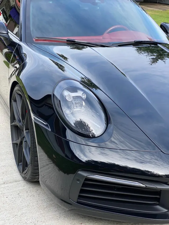 Reflektor i połyskująca maska czarnego Porsche 911